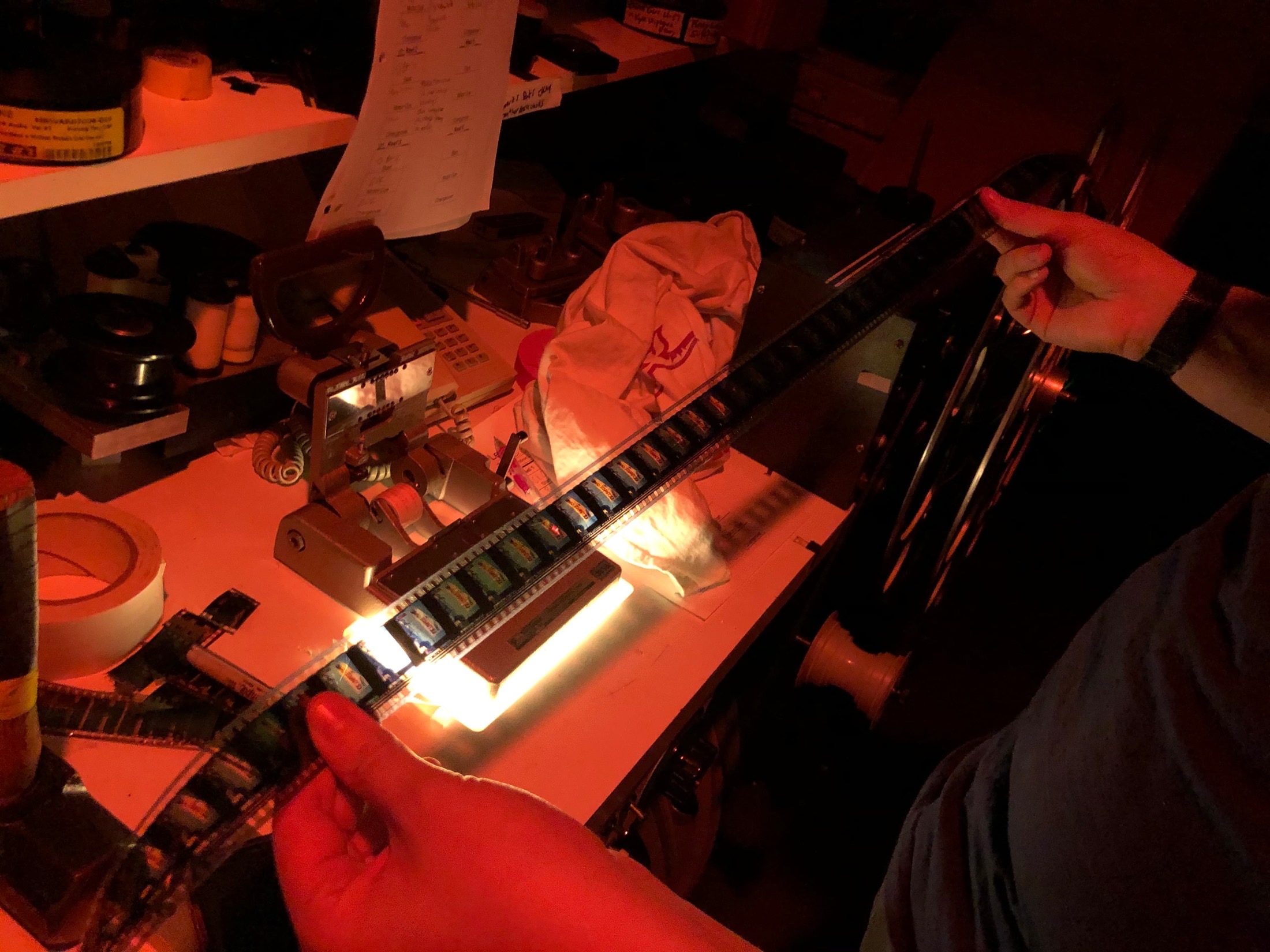 A projectionist inspecting and splicing together a new reel